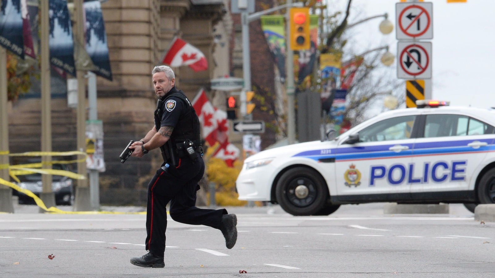 Un policier d'Ottawa court près du Parlement, arme au poing, le 22 octobre 2014. Un policier d'Ottawa court près du Parlement, arme au poing, le 22 octobre 2014.