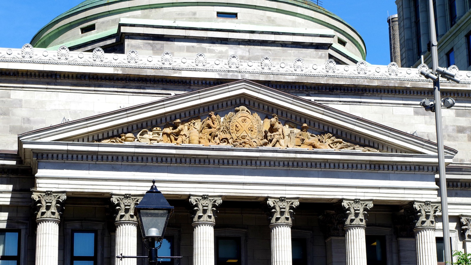 Un édifice aux allures romaines ou grecques dont la façade avant comprend des décorations qui semblent en bronze. Un édifice aux allures romaines ou grecques dont la façade avant comprend des décorations qui semblent en bronze.