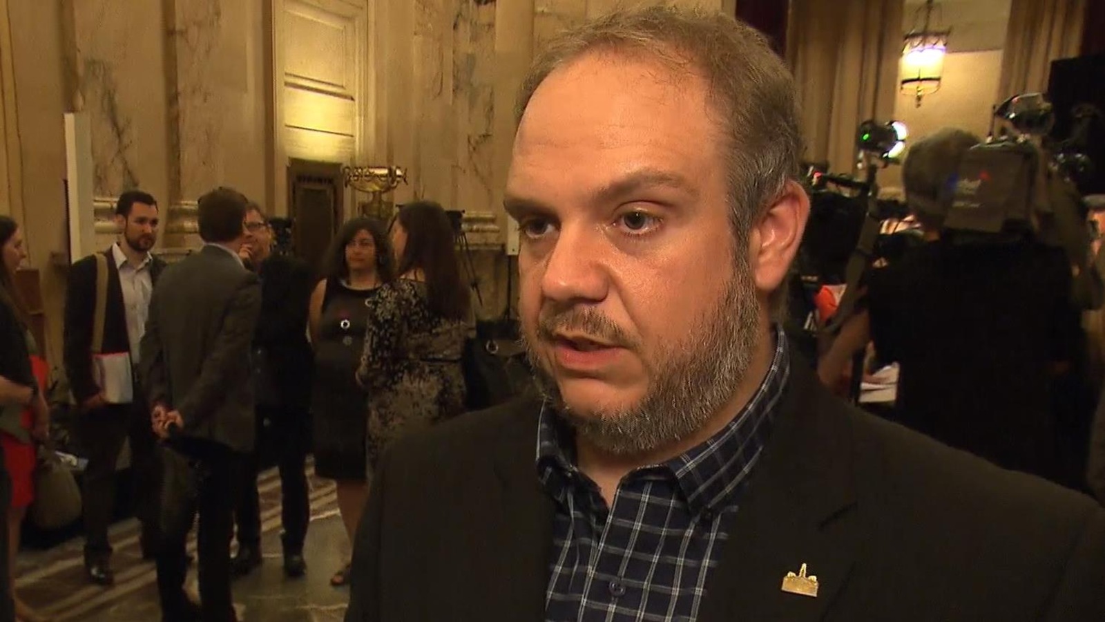 Benoit Dorais, maire de l'arrondissement du Sud-Ouest, en point de presse à l'hôtel de ville, avec un groupe de personnes en train de discuter à l'arrière. Benoit Dorais, maire de l'arrondissement du Sud-Ouest, en point de presse à l'hôtel de ville, avec un groupe de personnes en train de discuter à l'arrière.