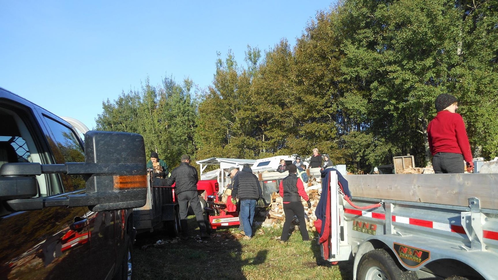 Des bénévoles s'affairent à remplir les remorques de bois de chauffage. Des bénévoles s'affairent à remplir les remorques de bois de chauffage.