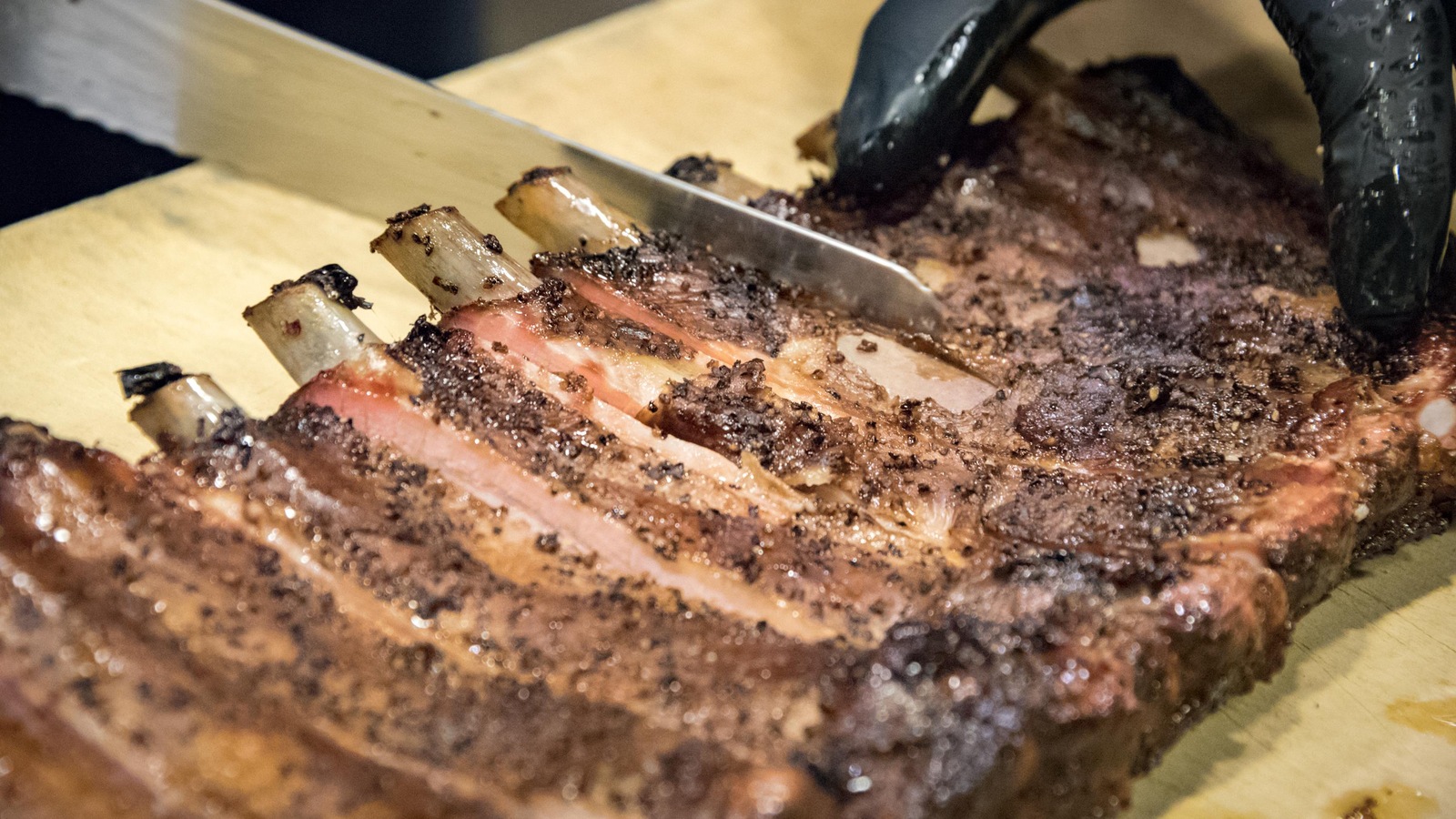 Des côtes de porc fumées sont tranchées au couteau Des côtes de porc fumées sont tranchées au couteau