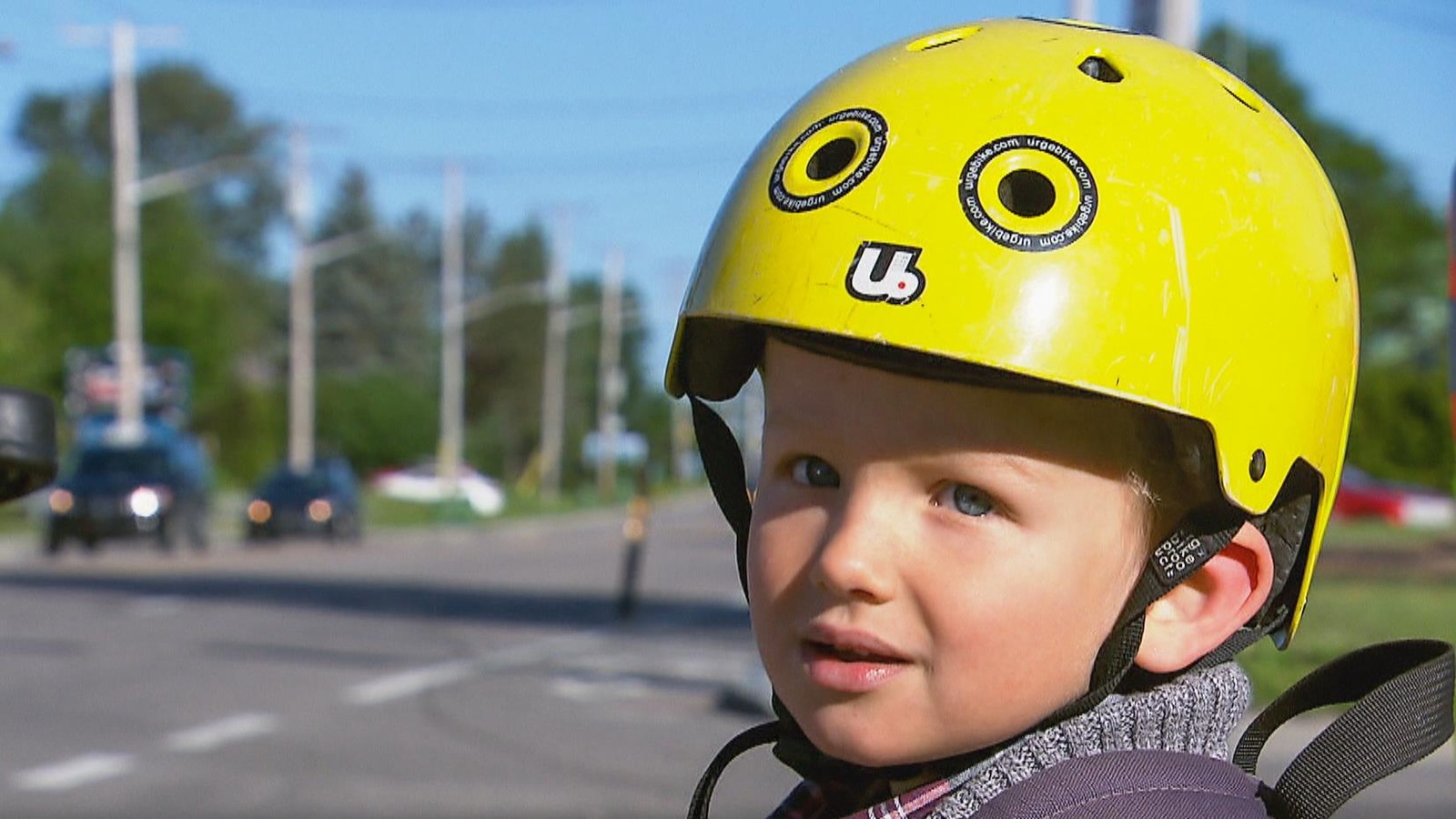 Un enfant portant un casque de vélo jaune regarde la caméra.