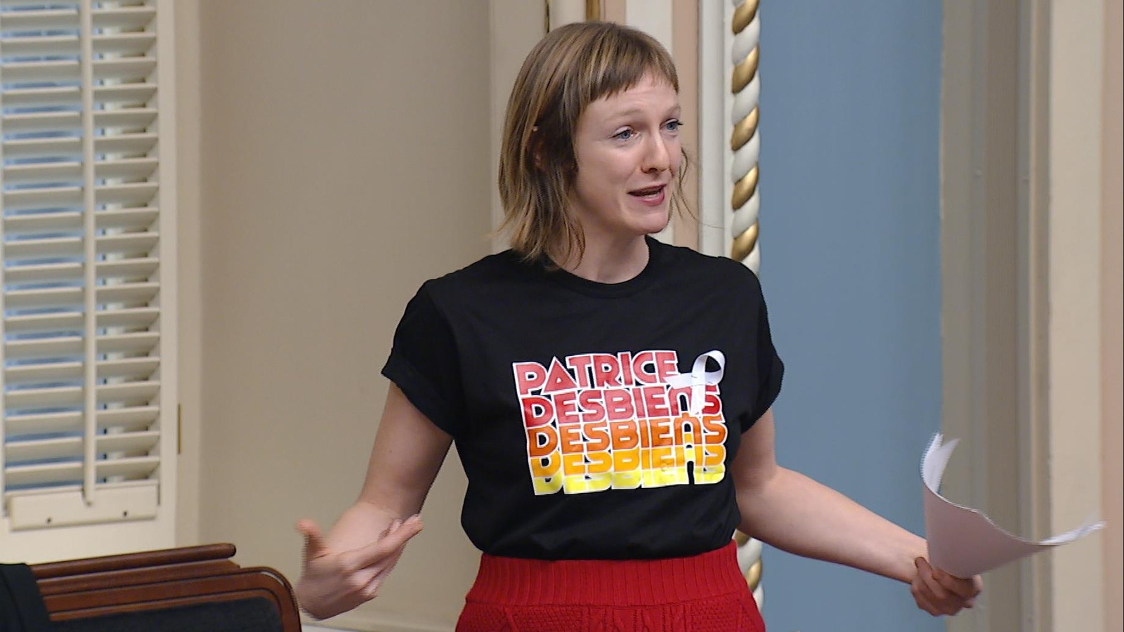 Catherine Dorion, à l'Assemblée nationale, est debout et porte un t-shirt sur lequel il est écrit Patrice Desbiens. Catherine Dorion, à l'Assemblée nationale, est debout et porte un t-shirt sur lequel il est écrit Patrice Desbiens.
