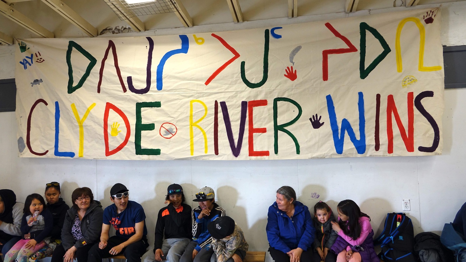 Une banderole blanche avec l’inscription en anglais « Clyde River gagne » est affichée dans le gymnase du centre communautaire. Une banderole blanche avec l’inscription en anglais « Clyde River gagne » est affichée dans le gymnase du centre communautaire.