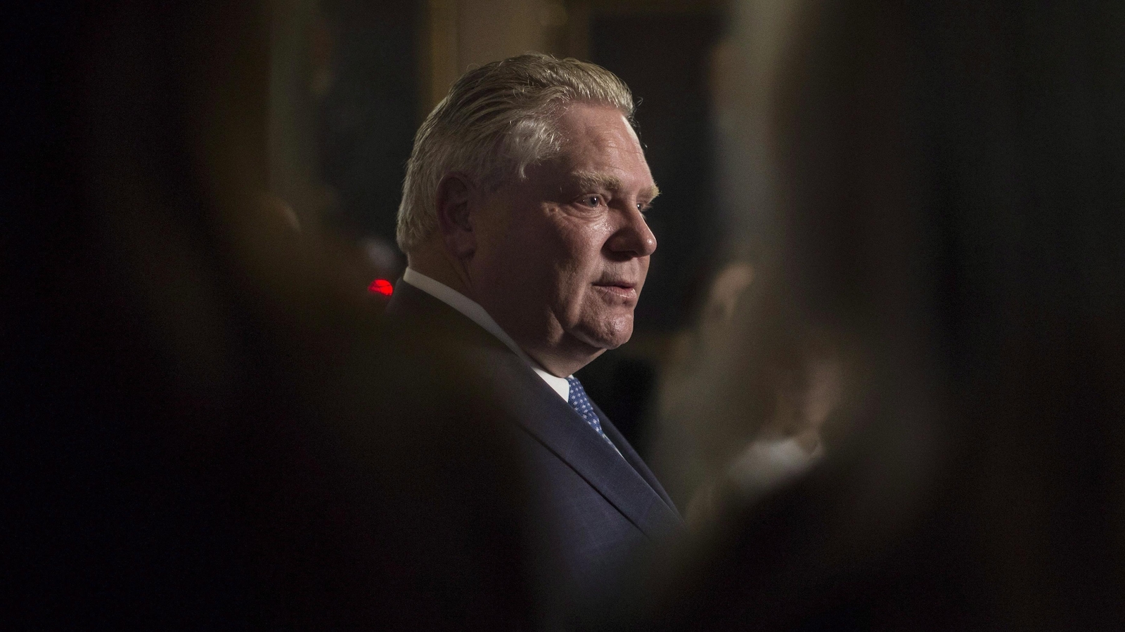 Doug Ford entre deux personnes de dos. Doug Ford entre deux personnes de dos.