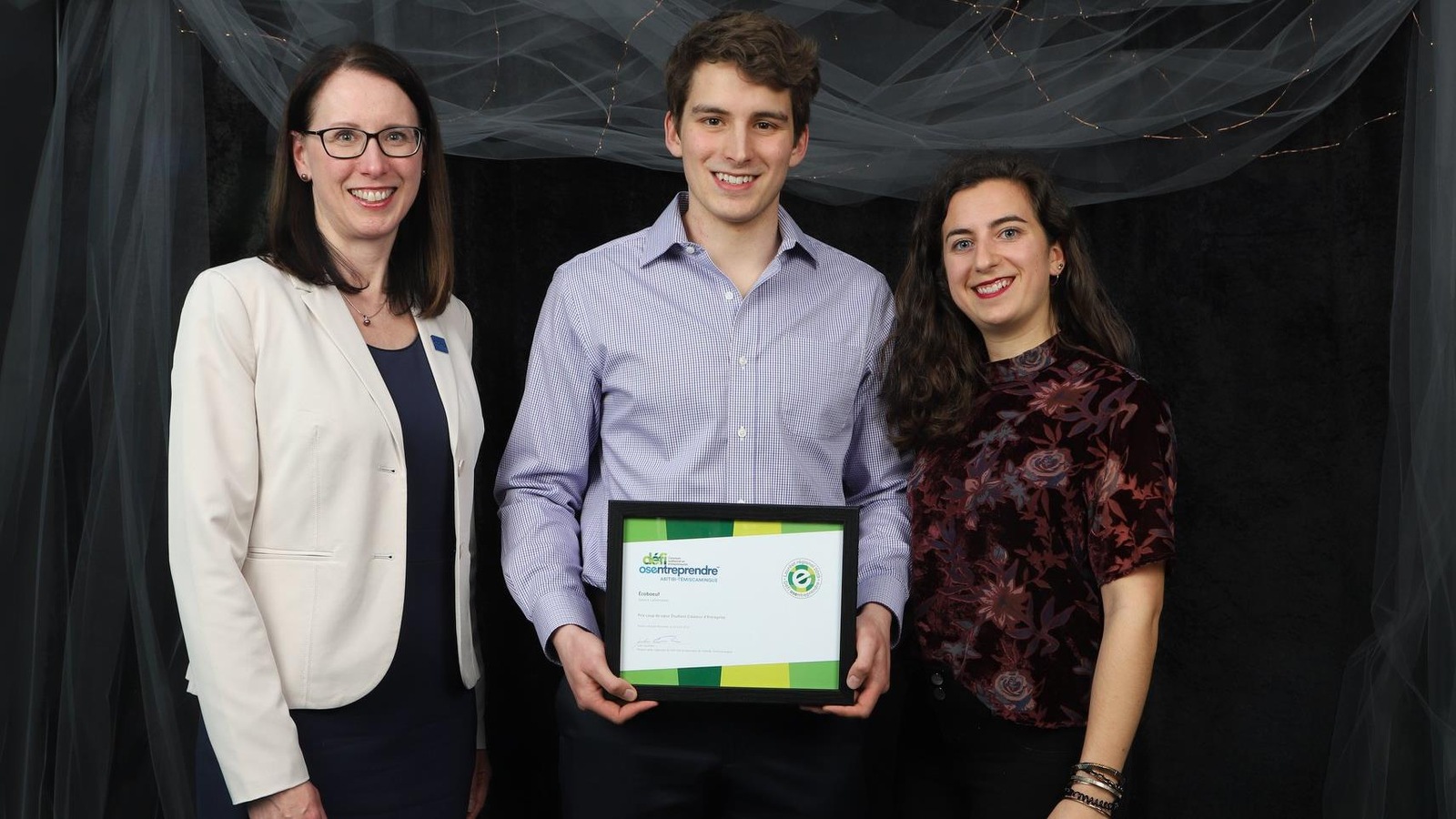 Un jeune homme et une jeune femme posent avec une femme remettant un prix lors du gala Défi Osentreprendre. Un jeune homme et une jeune femme posent avec une femme remettant un prix lors du gala Défi Osentreprendre.