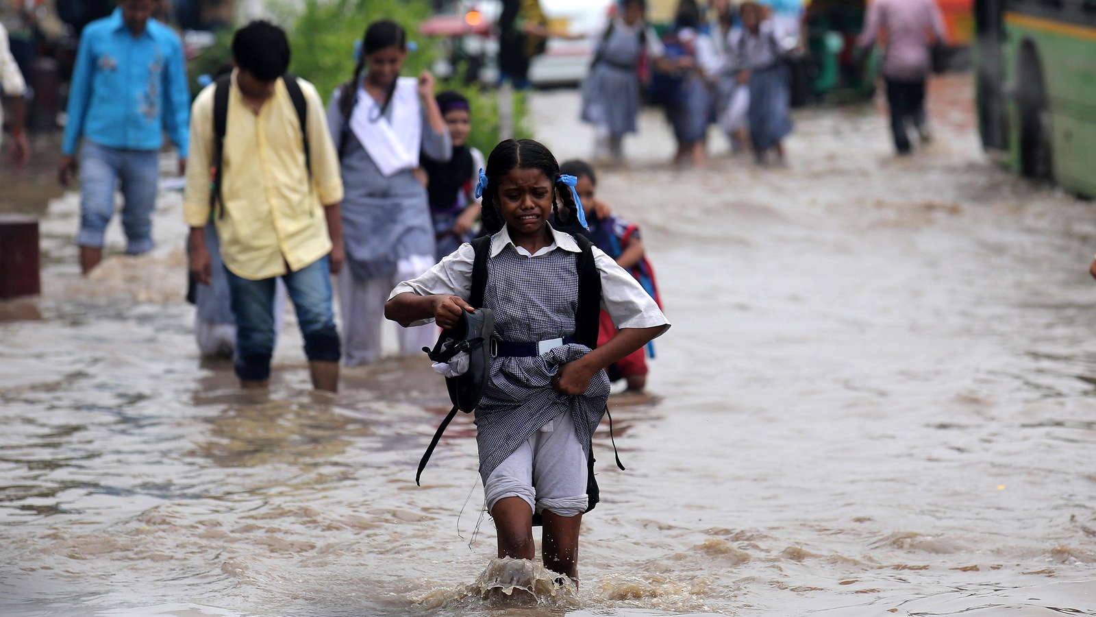 Une fillette avance dans la rue inondée, ses souliers à la main et une grimace au visage. Une fillette avance dans la rue inondée, ses souliers à la main et une grimace au visage.