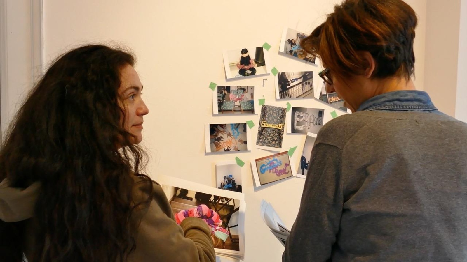 Deux femmes discutent et regardent les photos collées au mur. Deux femmes discutent et regardent les photos collées au mur.