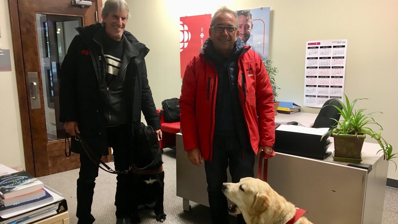Daniel Bonin et son chien Cadeau, avec Raymond Gignac et le chien à la retraite Fitch, posent dans le bureau de Radio-Canada. Daniel Bonin et son chien Cadeau, avec Raymond Gignac et le chien à la retraite Fitch, posent dans le bureau de Radio-Canada.