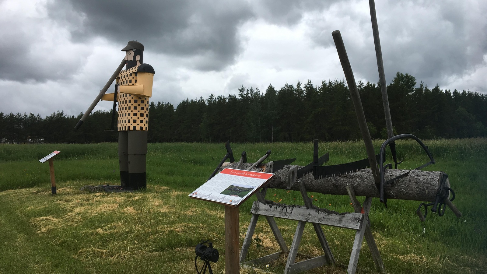 Une sculpture géante montre un homme à l'époque des bûcherons. Un panneau explicatif est placé devant. Une sculpture géante montre un homme à l'époque des bûcherons. Un panneau explicatif est placé devant.