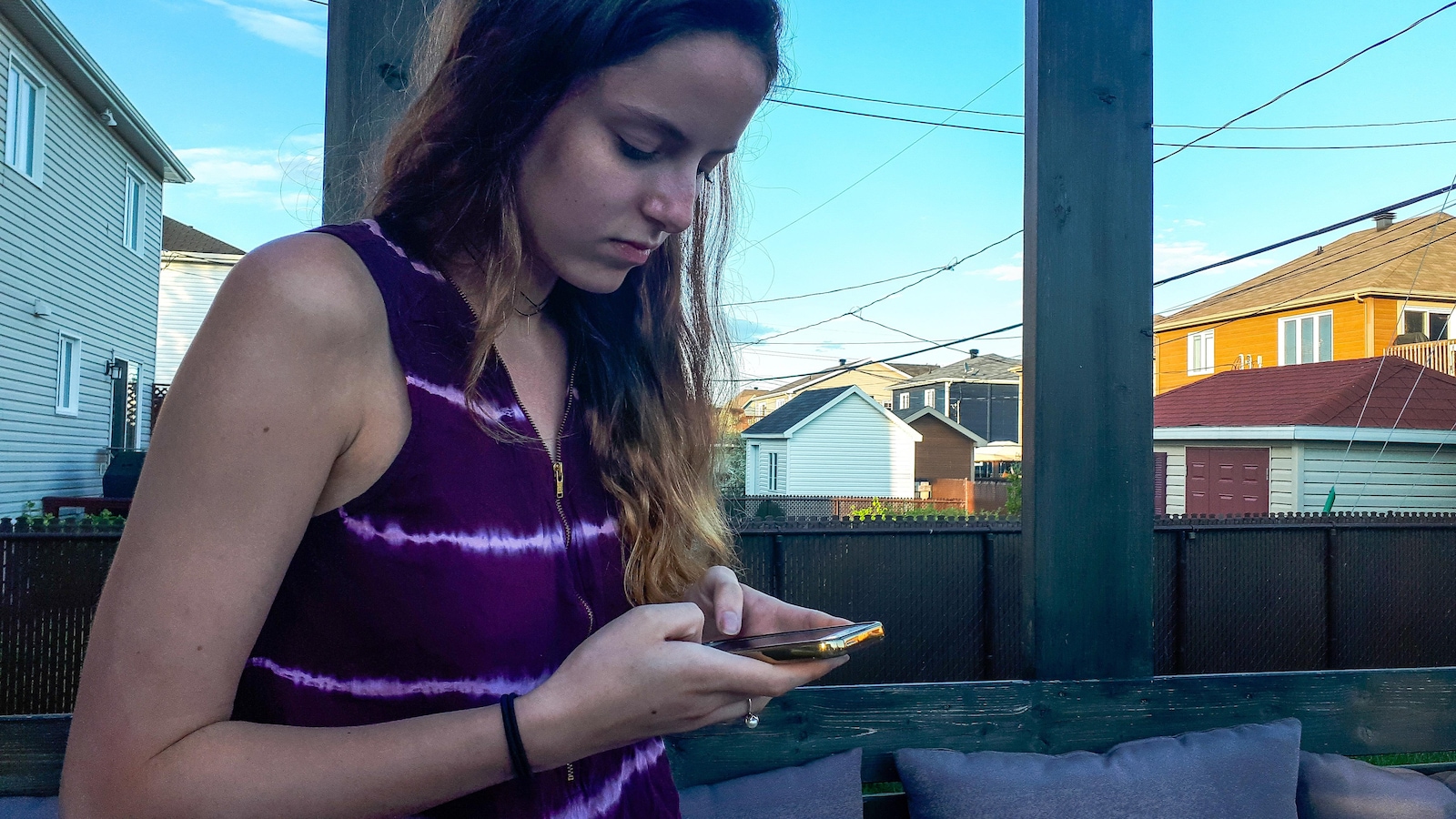 Jasmine Huot-McCann regarde un téléphone cellulaire assiste sur la terrasse de la maison de son père Jasmine Huot-McCann regarde un téléphone cellulaire assiste sur la terrasse de la maison de son père