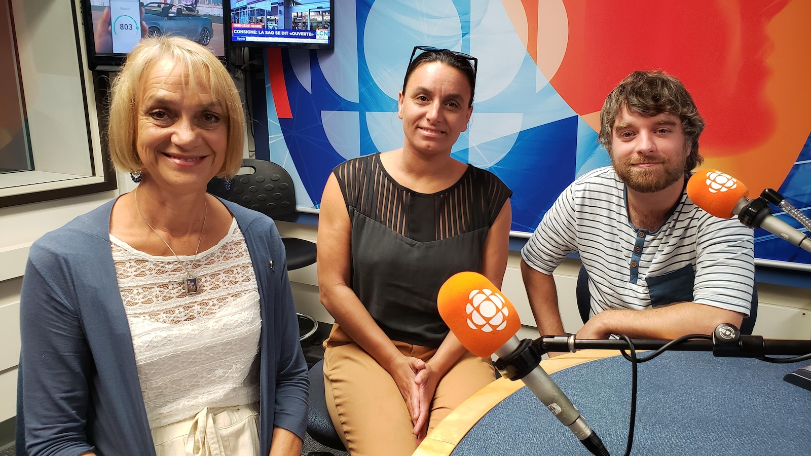 Un homme et deux femmes se trouvent dans un studio de Radio-Canada pour y participer à une table ronde. Un homme et deux femmes se trouvent dans un studio de Radio-Canada pour y participer à une table ronde.