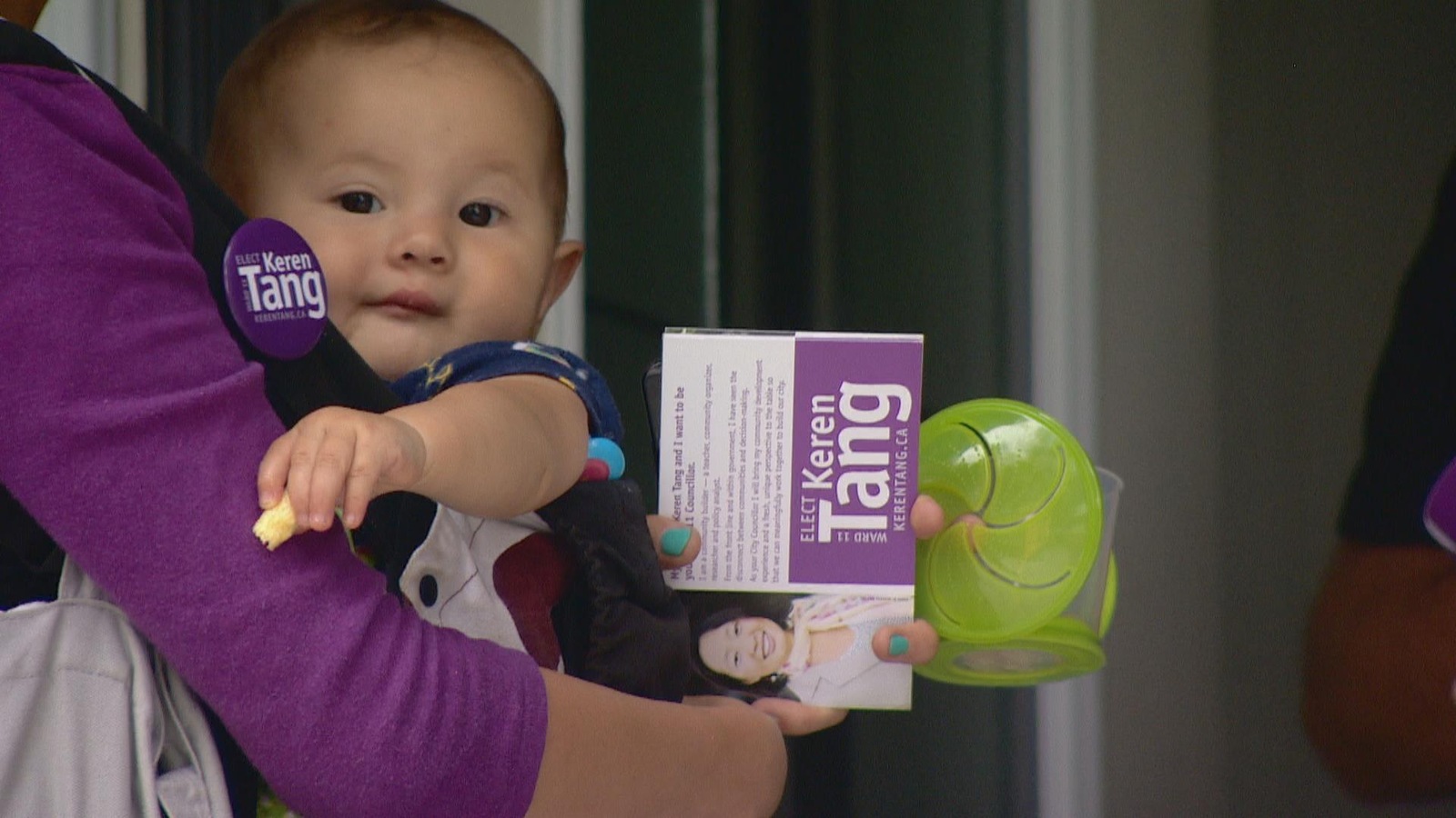 Un bébé dans son porte bébé, sa mère qui tient des pamphlets de sa campagne en main Un bébé dans son porte bébé, sa mère qui tient des pamphlets de sa campagne en main