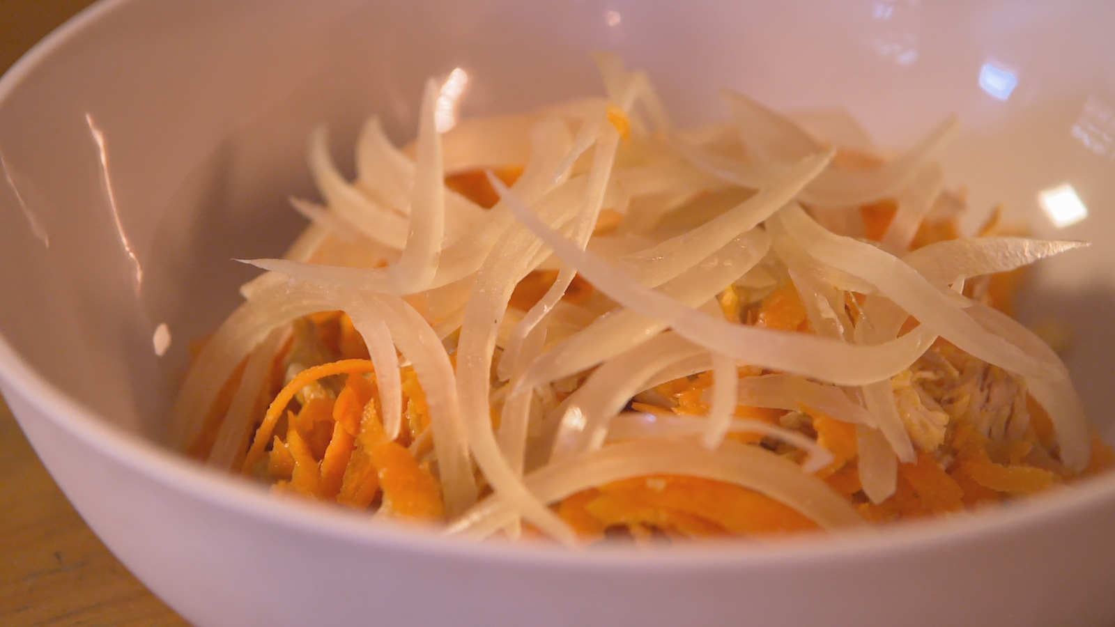 Une salade d'oignons marinés et de carottes et poulet dans un bol Une salade d'oignons marinés et de carottes et poulet dans un bol
