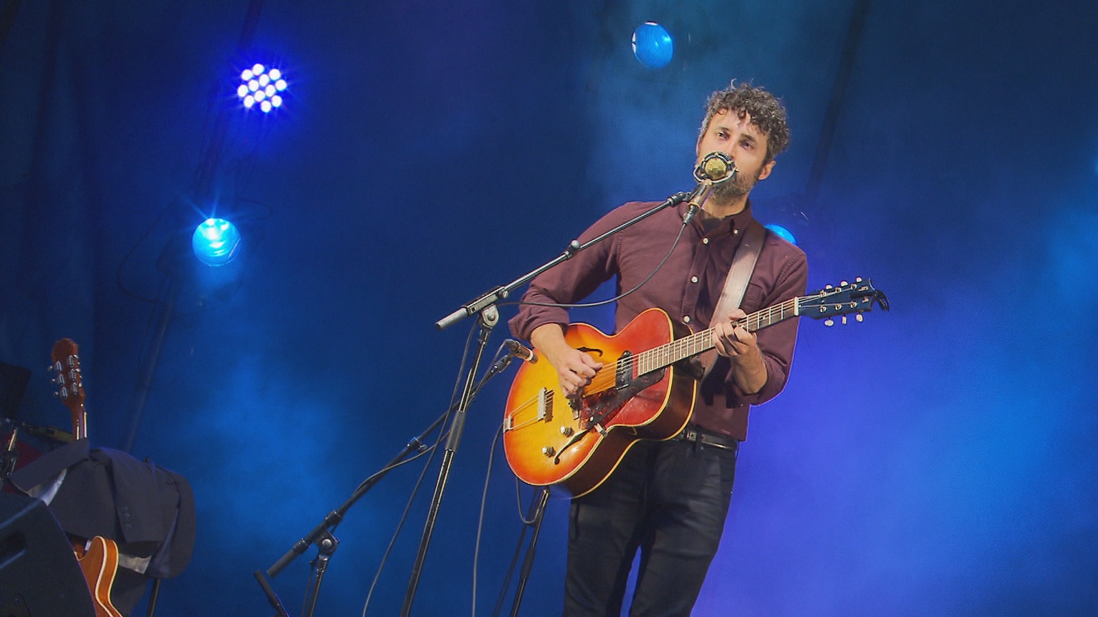 Il chante, avec sa guitare, seul sur scène. Il chante, avec sa guitare, seul sur scène.