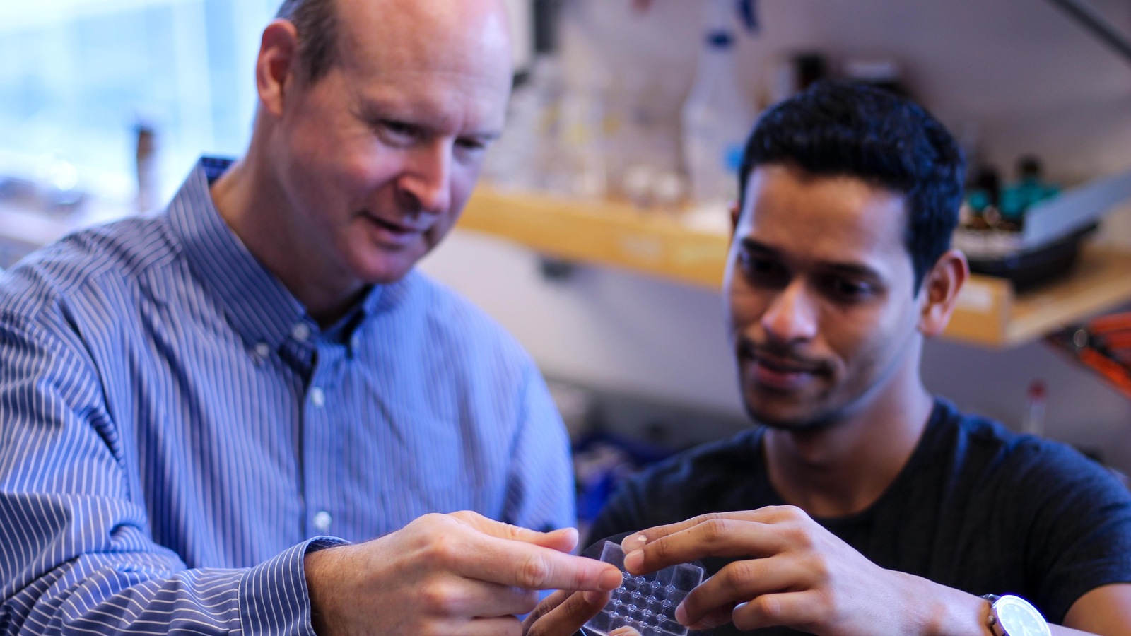 Deux hommes tiennent un capteur tactile dans un laboratoire. Deux hommes tiennent un capteur tactile dans un laboratoire.