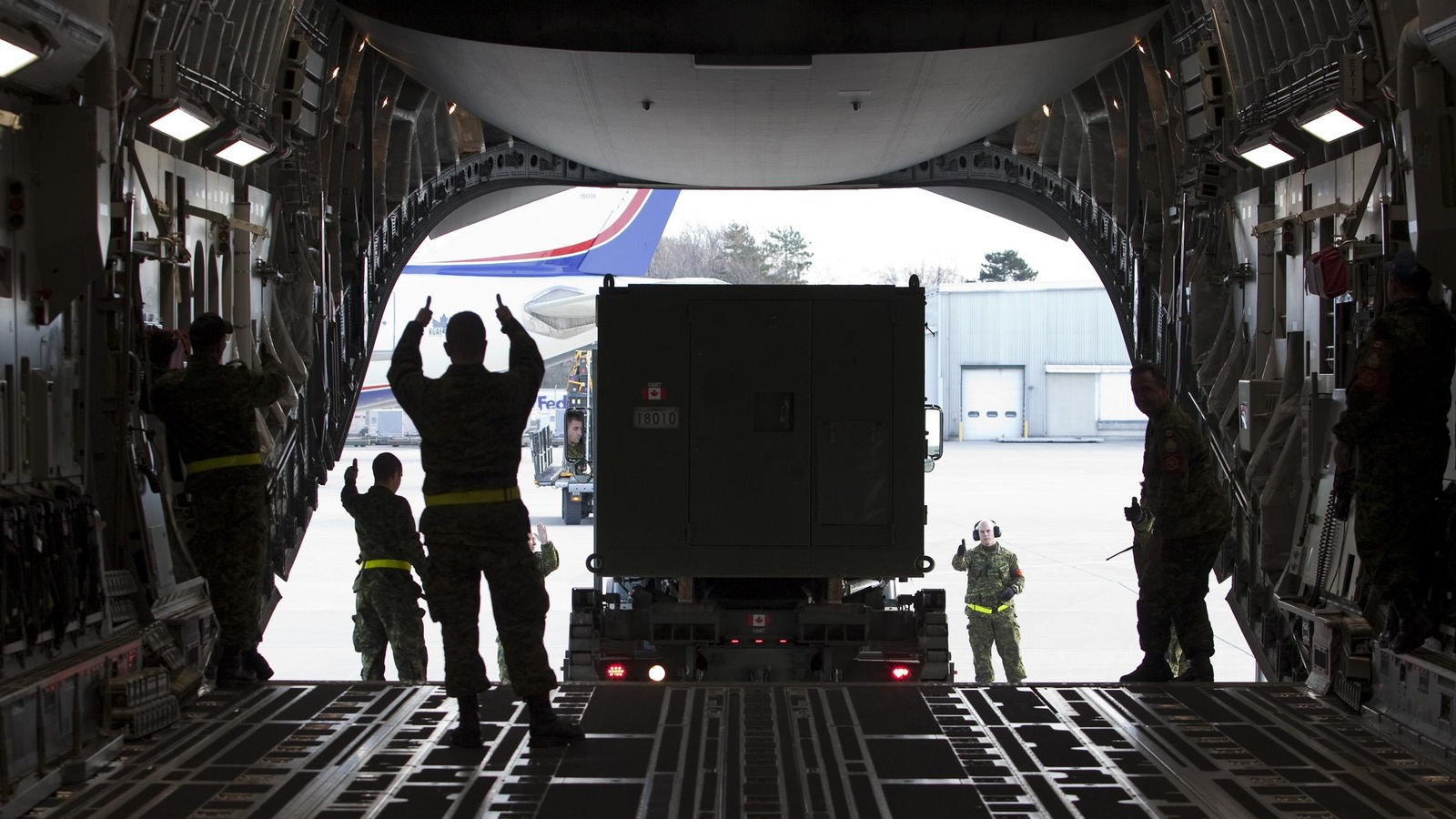 Des militaires chargent un conteneur dans un avion. Des militaires chargent un conteneur dans un avion.