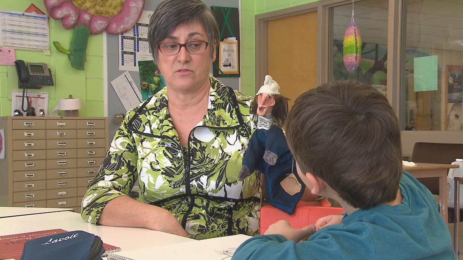 Une enseignante tient une marionnette dans ses mains et parle à un élève. Une enseignante tient une marionnette dans ses mains et parle à un élève.