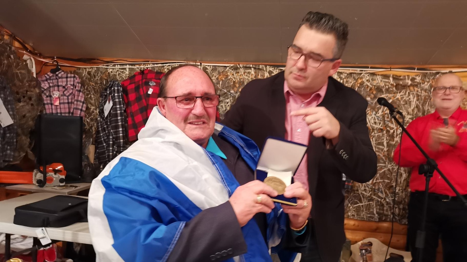 Rémi Gagné, drapé du drapeau du Québec, tient la médaille dans ses mains. Rémi Gagné, drapé du drapeau du Québec, tient la médaille dans ses mains.