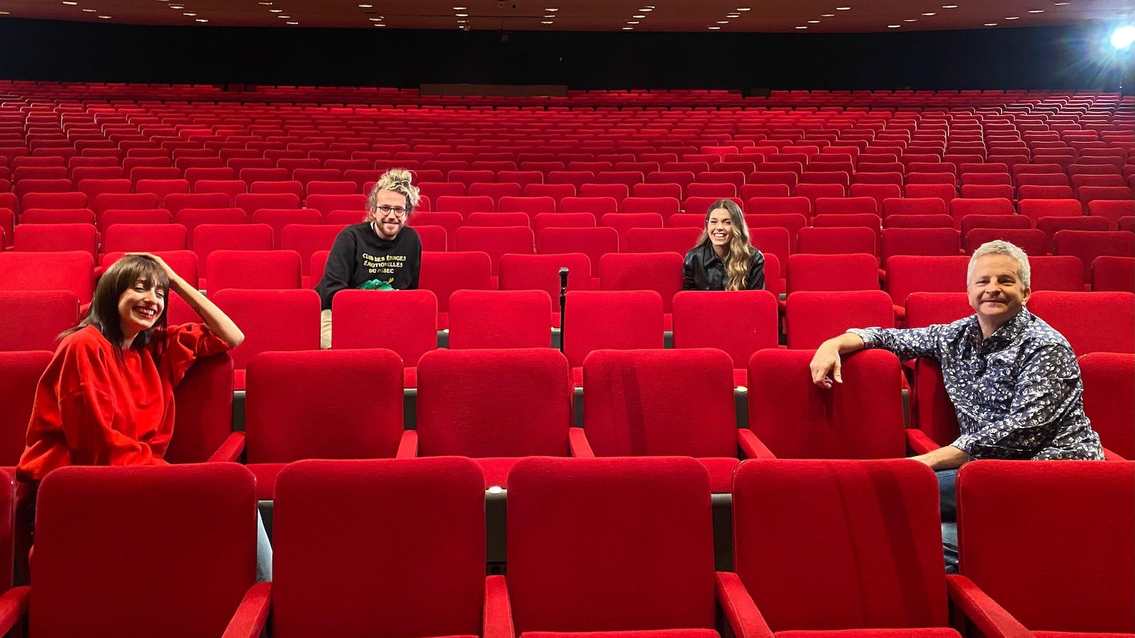 Les quatre personnes sont assises dans une salle de spectacle et à distance. Les quatre personnes sont assises dans une salle de spectacle et à distance.