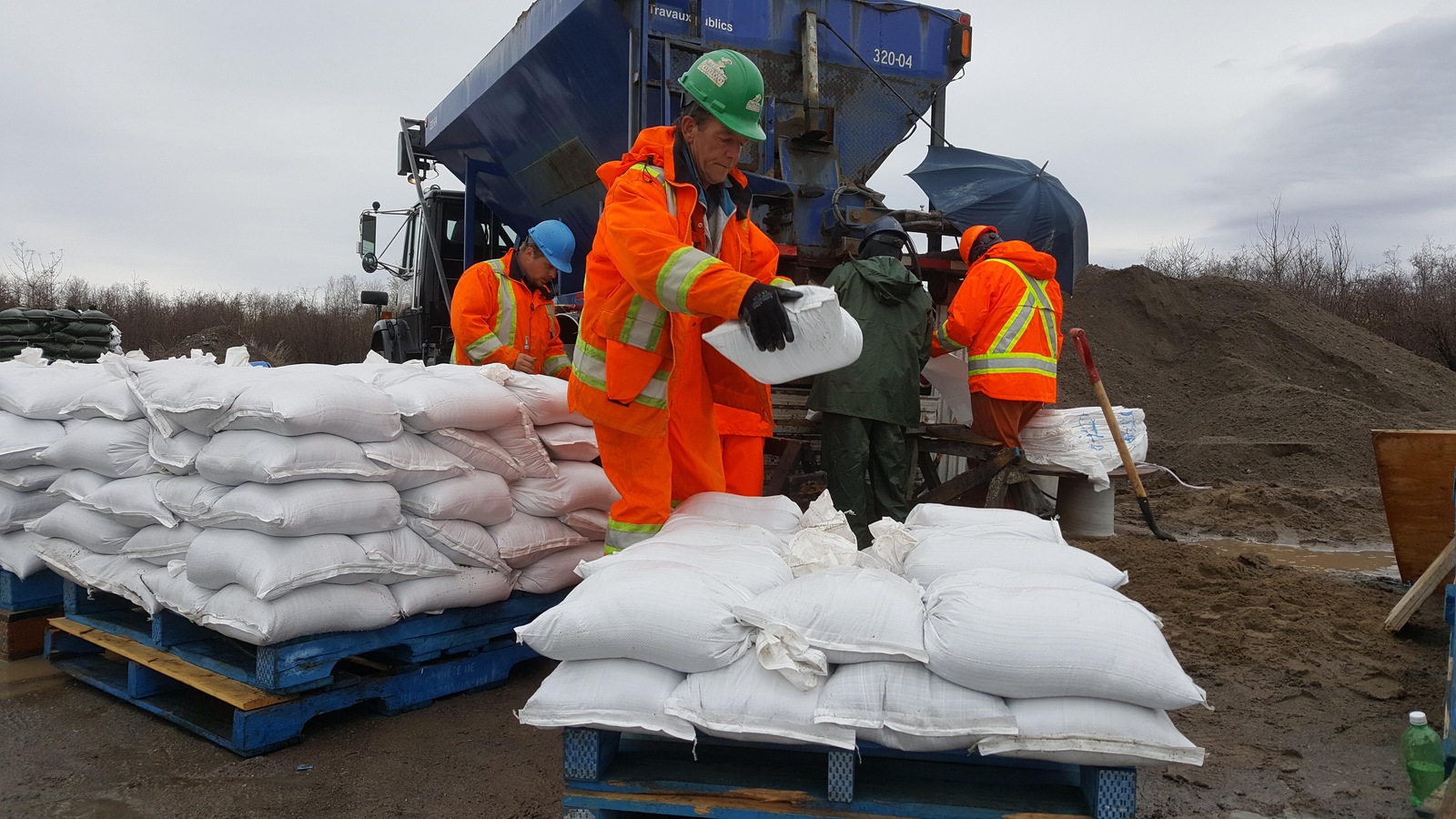 Des travailleurs remplissent des sacs de sable à Saint-Gédéon. Des travailleurs remplissent des sacs de sable à Saint-Gédéon.