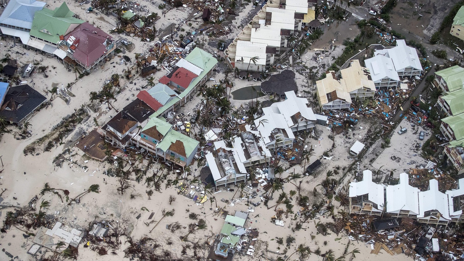 Une plage dévastée de la partie néerlandaise de l'île de Saint-Martin : des bâtiments ont été détruits, et des arbres balayés sur le sable. Une plage dévastée de la partie néerlandaise de l'île de Saint-Martin : des bâtiments ont été détruits, et des arbres balayés sur le sable.