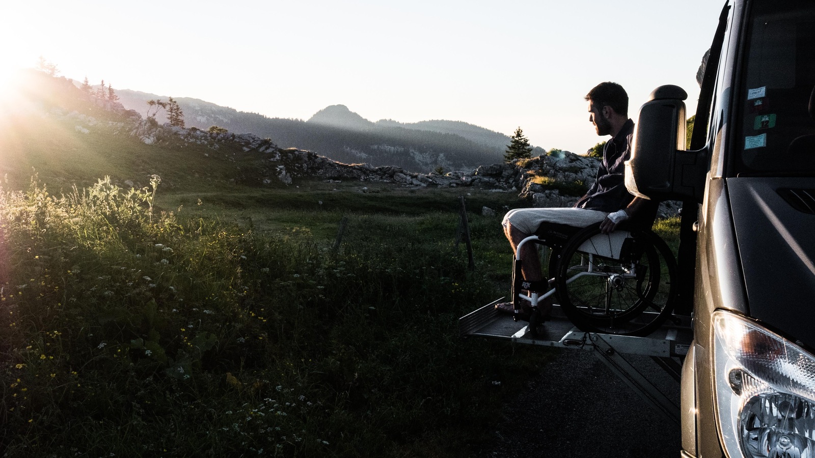 Le jeune homme est assis dans son fauteuil roulant, qui est installé sur la rampe du camion. Le jeune homme est assis dans son fauteuil roulant, qui est installé sur la rampe du camion.
