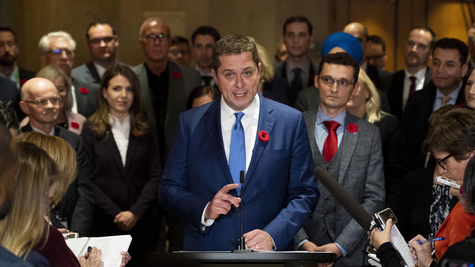 Entourés de députés conservateurs, Andrew Scheer prononce un discours face aux journalistes. Entourés de députés conservateurs, Andrew Scheer prononce un discours face aux journalistes.