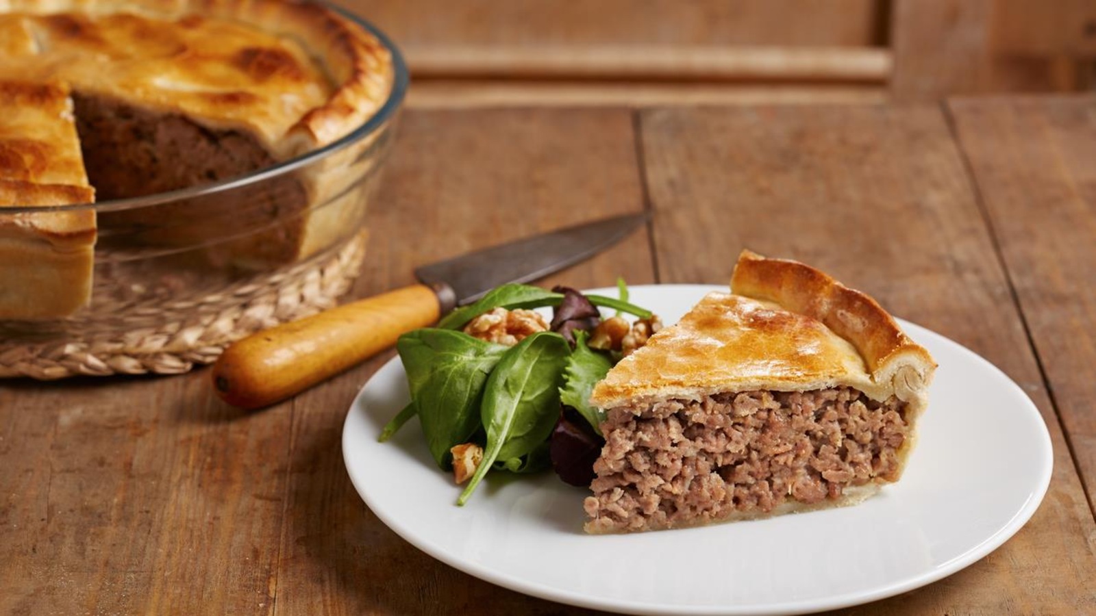 Part de tourtière présentée dans une assiette avec un peu de salade Part de tourtière présentée dans une assiette avec un peu de salade