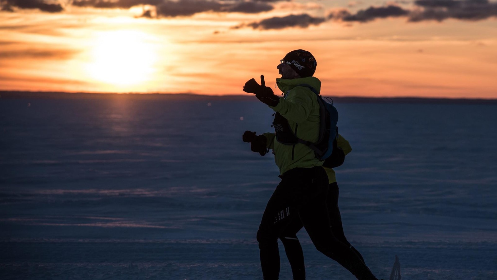 Un homme court sur la neige. Il y a un couché du soleil. Un homme court sur la neige. Il y a un couché du soleil.