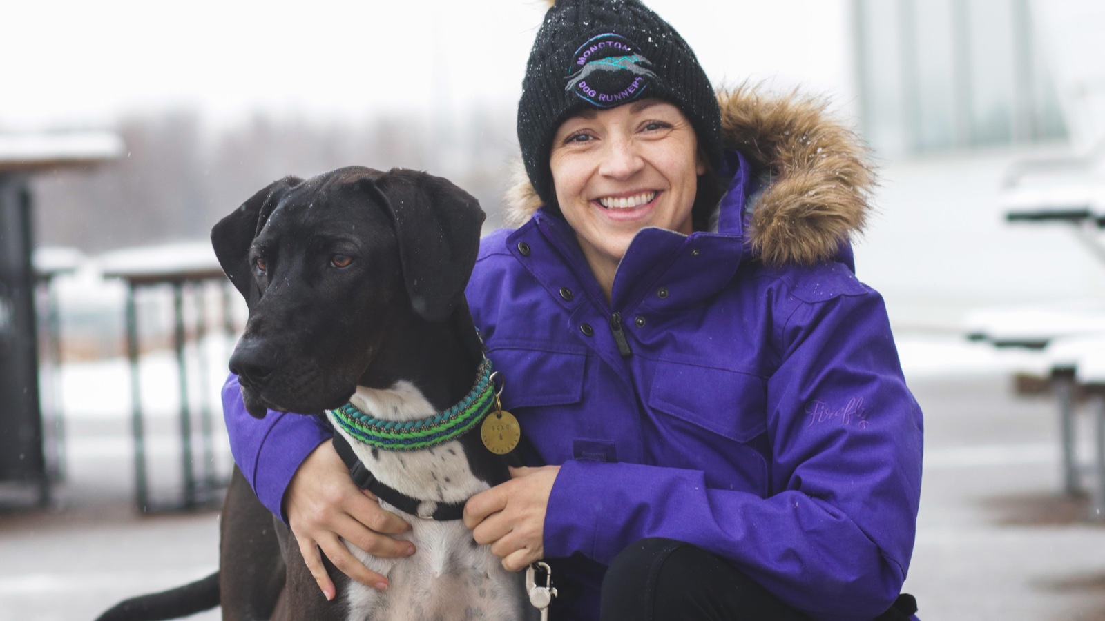 Une femme souriante avec son chien alors qu'il neige. Une femme souriante avec son chien alors qu'il neige.