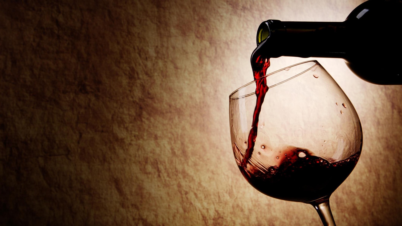 Du vin rouge est versé dans un verre à vin. Du vin rouge est versé dans un verre à vin.