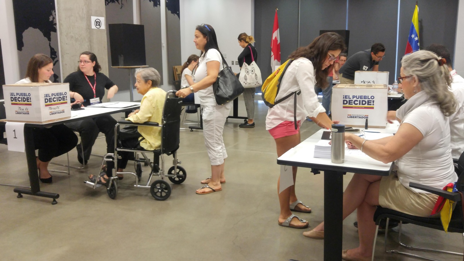 Plusieurs personnes remplissent leur bulletin de vote, qu'ils déposent ensuite dans une boîte où on peut lire « Le peuple décide! » Plusieurs personnes remplissent leur bulletin de vote, qu'ils déposent ensuite dans une boîte où on peut lire « Le peuple décide! »