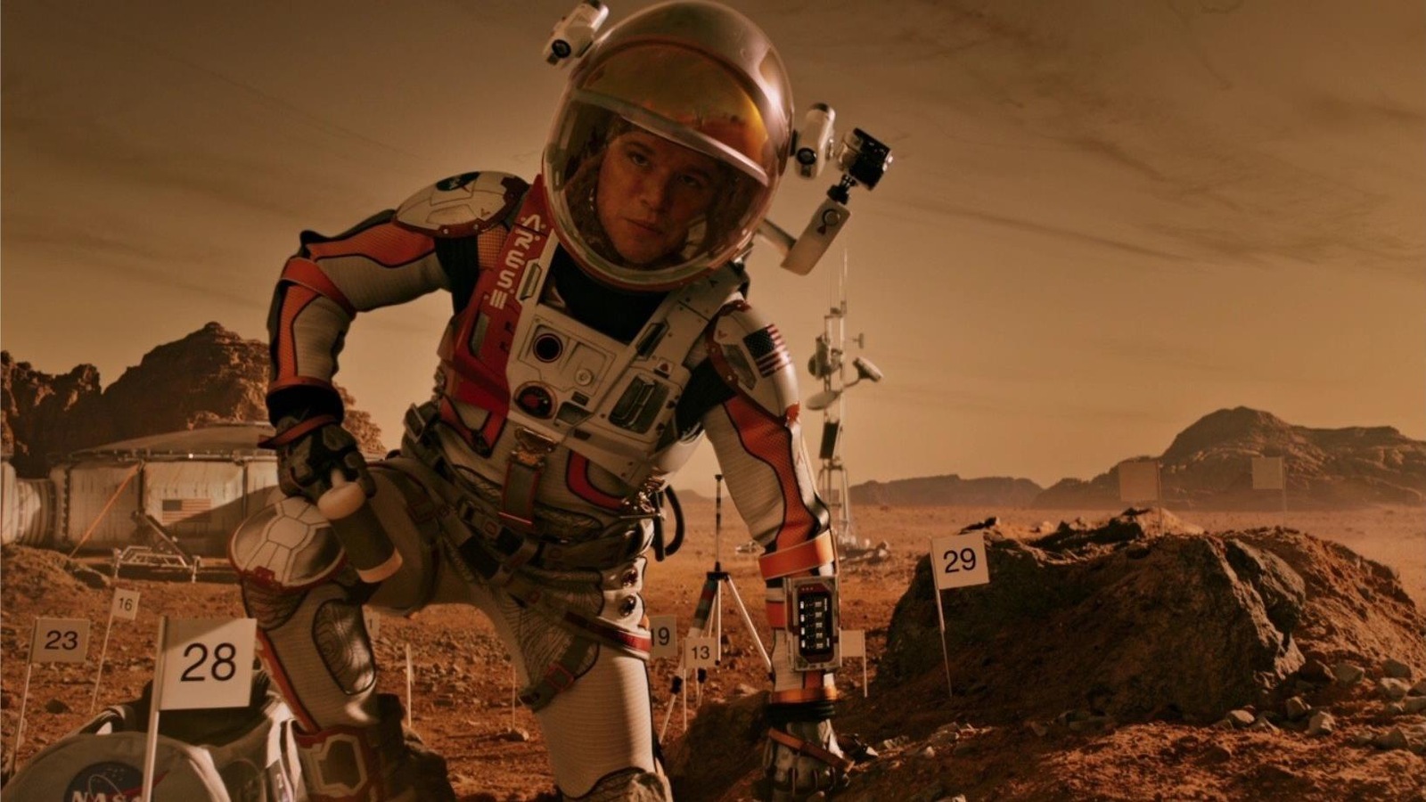 Un homme en tenue d'astronaute, un genou à terre, sur une terre rouge. Un homme en tenue d'astronaute, un genou à terre, sur une terre rouge.