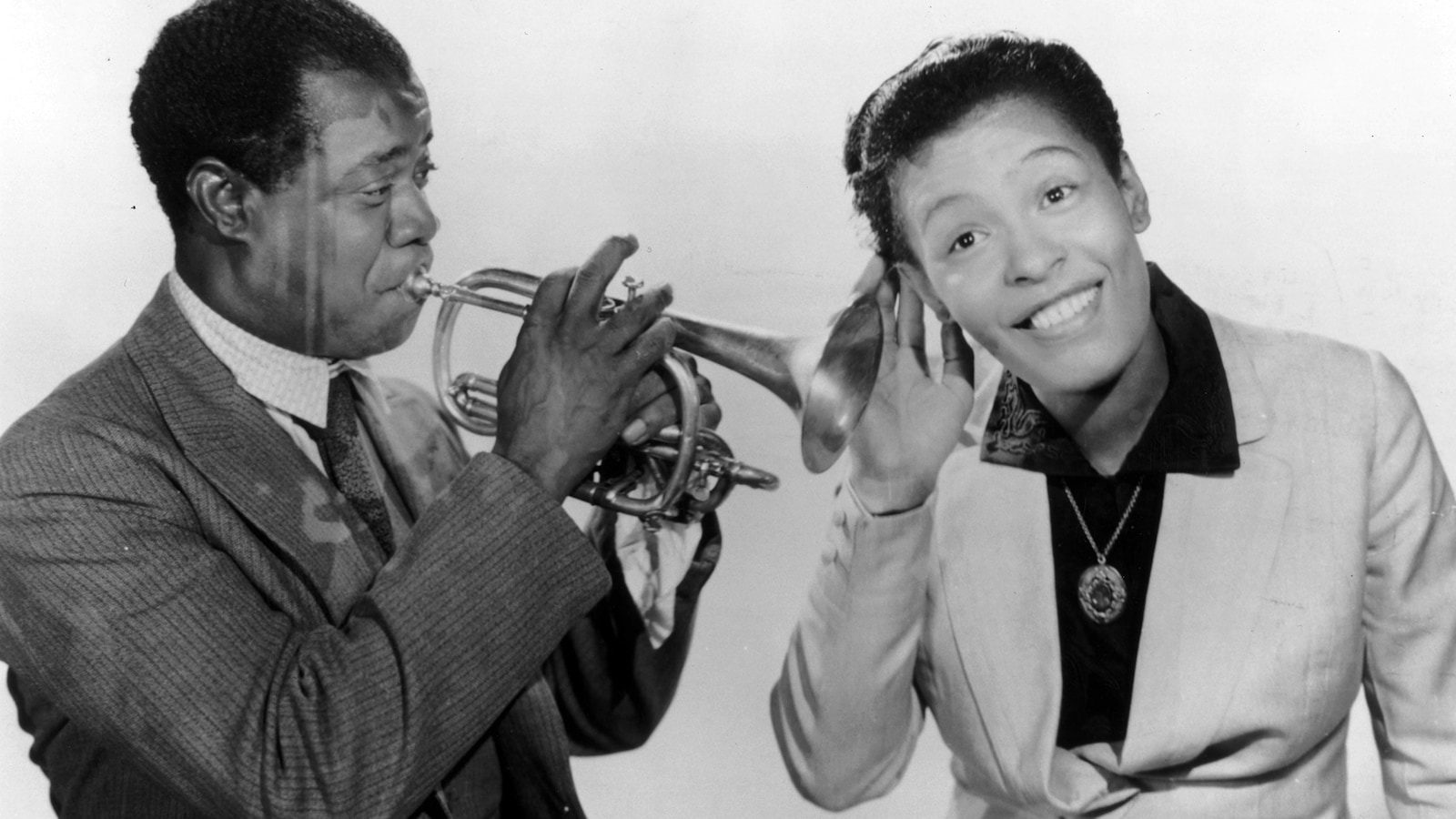 La chanteuse Billie Holiday tend son oreille vers la trompette de Louis Armstrong qui joue dans son instrument. La chanteuse Billie Holiday tend son oreille vers la trompette de Louis Armstrong qui joue dans son instrument.