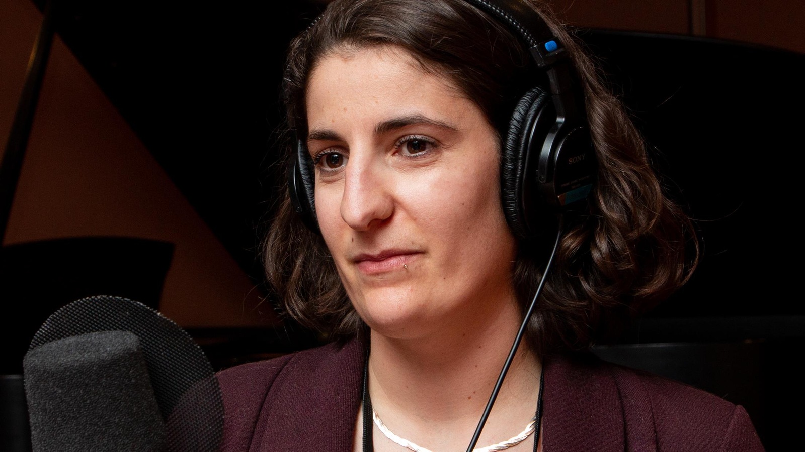 La jeune femme porte des écouteurs et parle dans un micro à la radio. La jeune femme porte des écouteurs et parle dans un micro à la radio.
