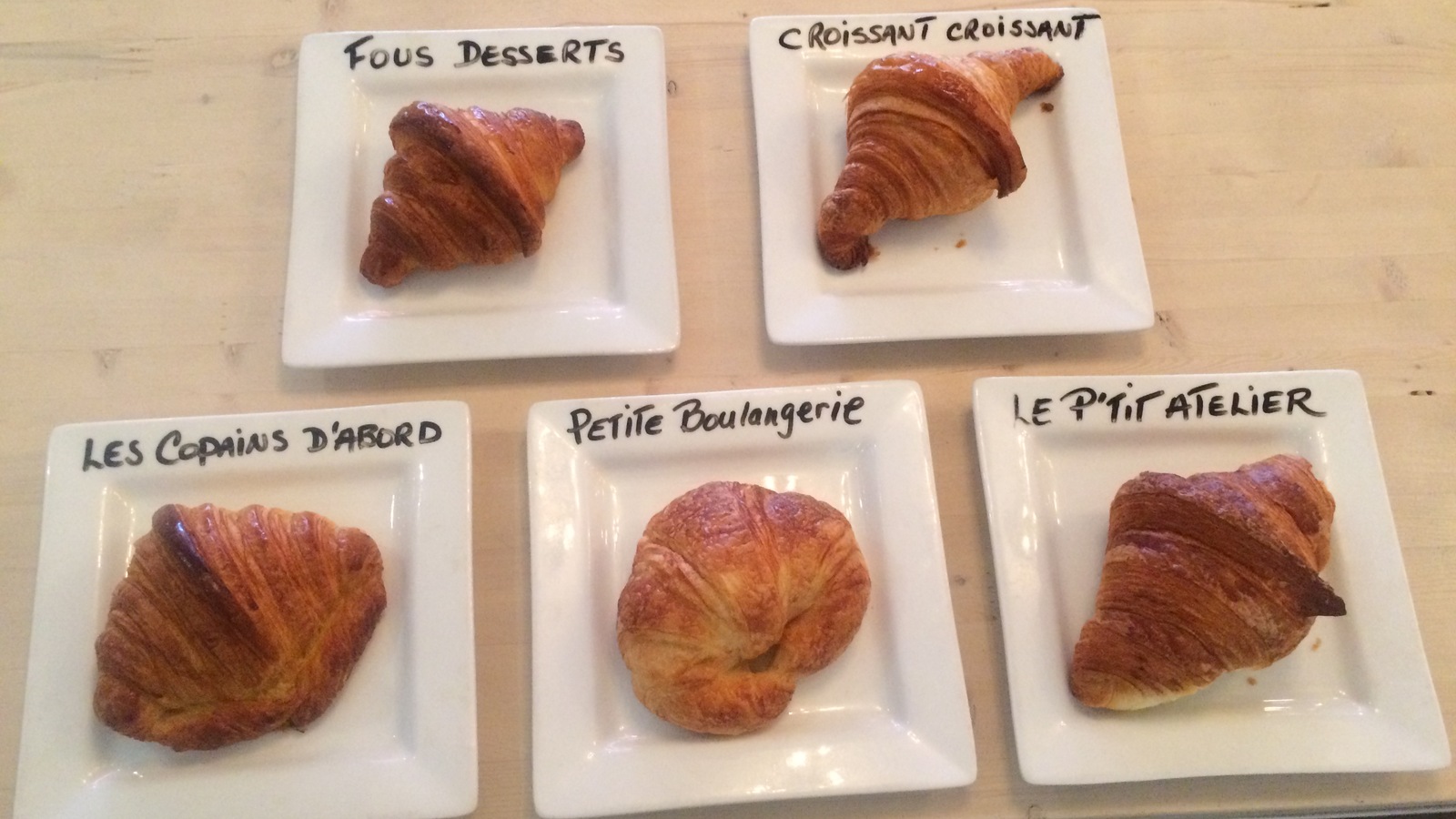Cinq croissants de cinq boulangeries de Montréal sont identifiés sur des assiettes Cinq croissants de cinq boulangeries de Montréal sont identifiés sur des assiettes