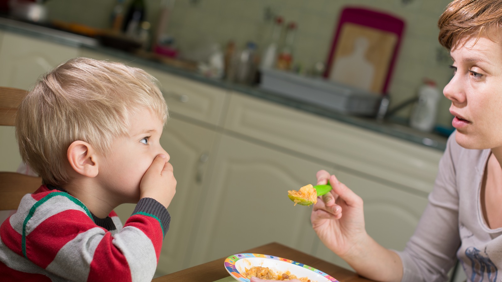 Une mère tente de faire manger son enfant âgé de 3 ou 4 ans. Une mère tente de faire manger son enfant âgé de 3 ou 4 ans.