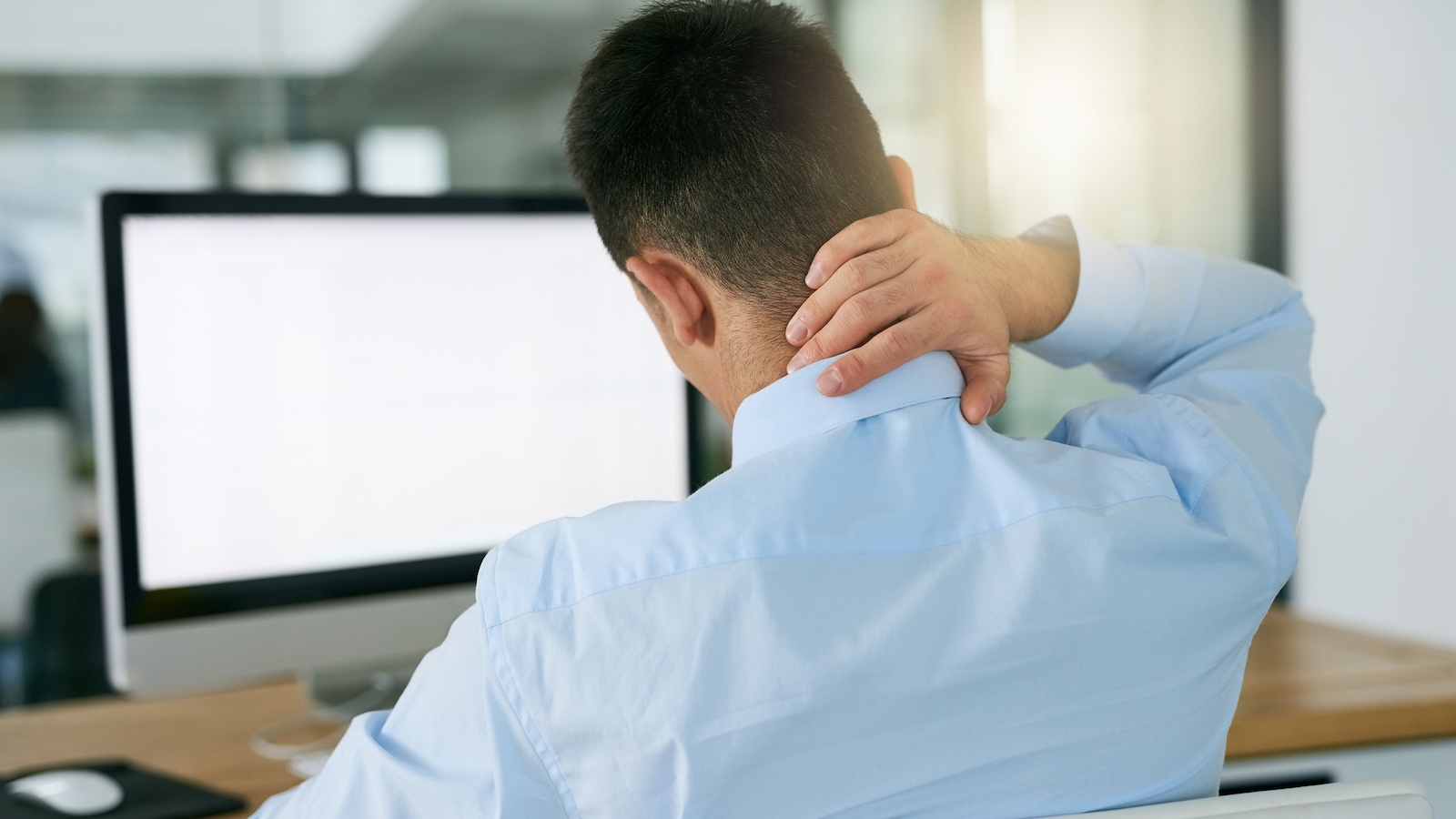 Un homme éprouve de la douleur au cou devant son ordinateur. Un homme éprouve de la douleur au cou devant son ordinateur.