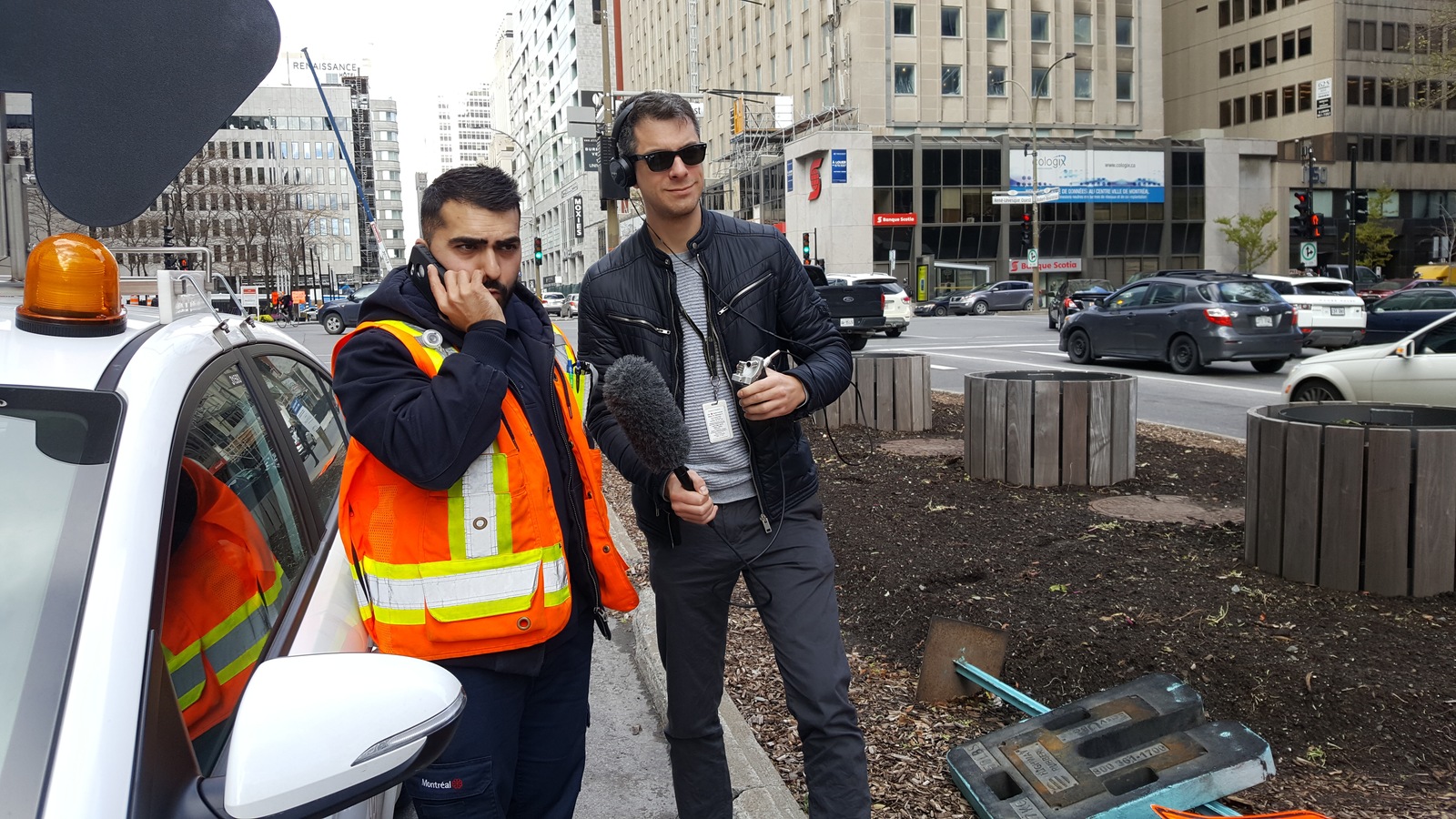 Un homme portant un dossard orange parle au cellulaire sur le bord d'une rue. Un homme portant un dossard orange parle au cellulaire sur le bord d'une rue.
