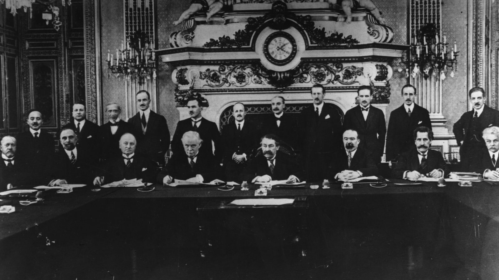 Des hommes cravatés se tiennent devant une table devant un décor luxueux. Des hommes cravatés se tiennent devant une table devant un décor luxueux.