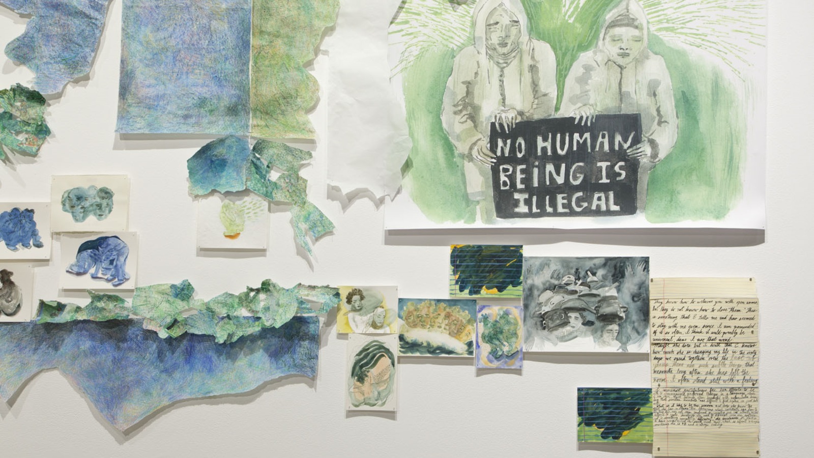 Dessins, écritures sur papier et peintures représentant des migrants. On peut lire : « Aucun être humain n'est illégal ». Dessins, écritures sur papier et peintures représentant des migrants. On peut lire : « Aucun être humain n'est illégal ».