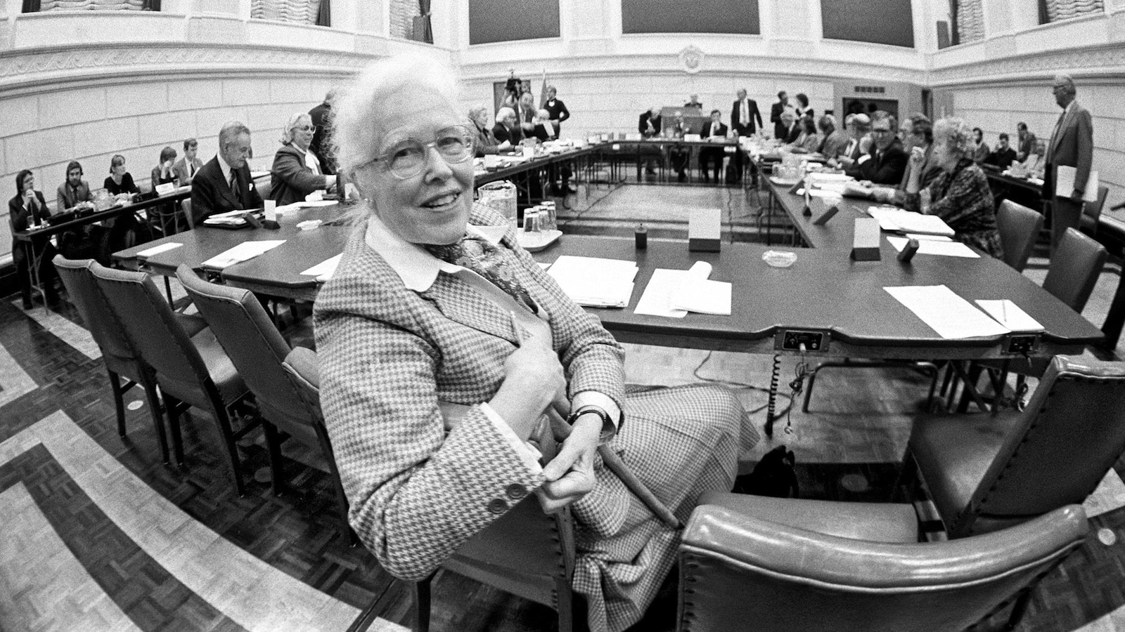 Photo en noir et blanc d'une femme âgée qui regarde la caméra dans une salle d'audience. Photo en noir et blanc d'une femme âgée qui regarde la caméra dans une salle d'audience.