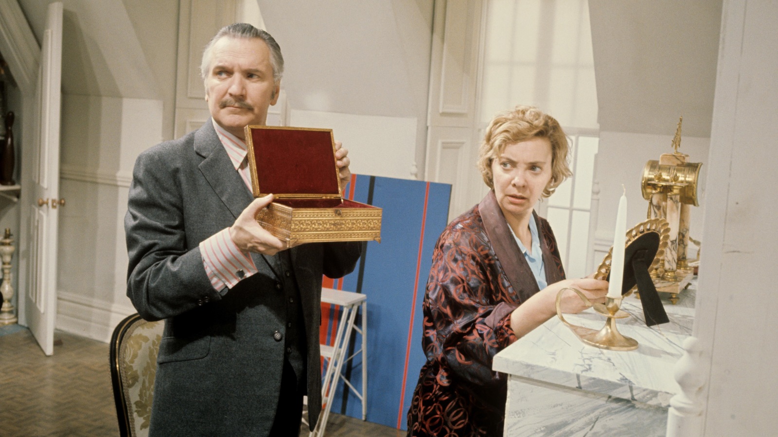 Un homme tenant un petit coffre ouvert et une femme postée devant une console regardent hors-champ vers leur droite dans cette photo de la pièce <i>Encore cinq minutes</i>, en 1970. Un homme tenant un petit coffre ouvert et une femme postée devant une console regardent hors-champ vers leur droite dans cette photo de la pièce <i>Encore cinq minutes</i>, en 1970.