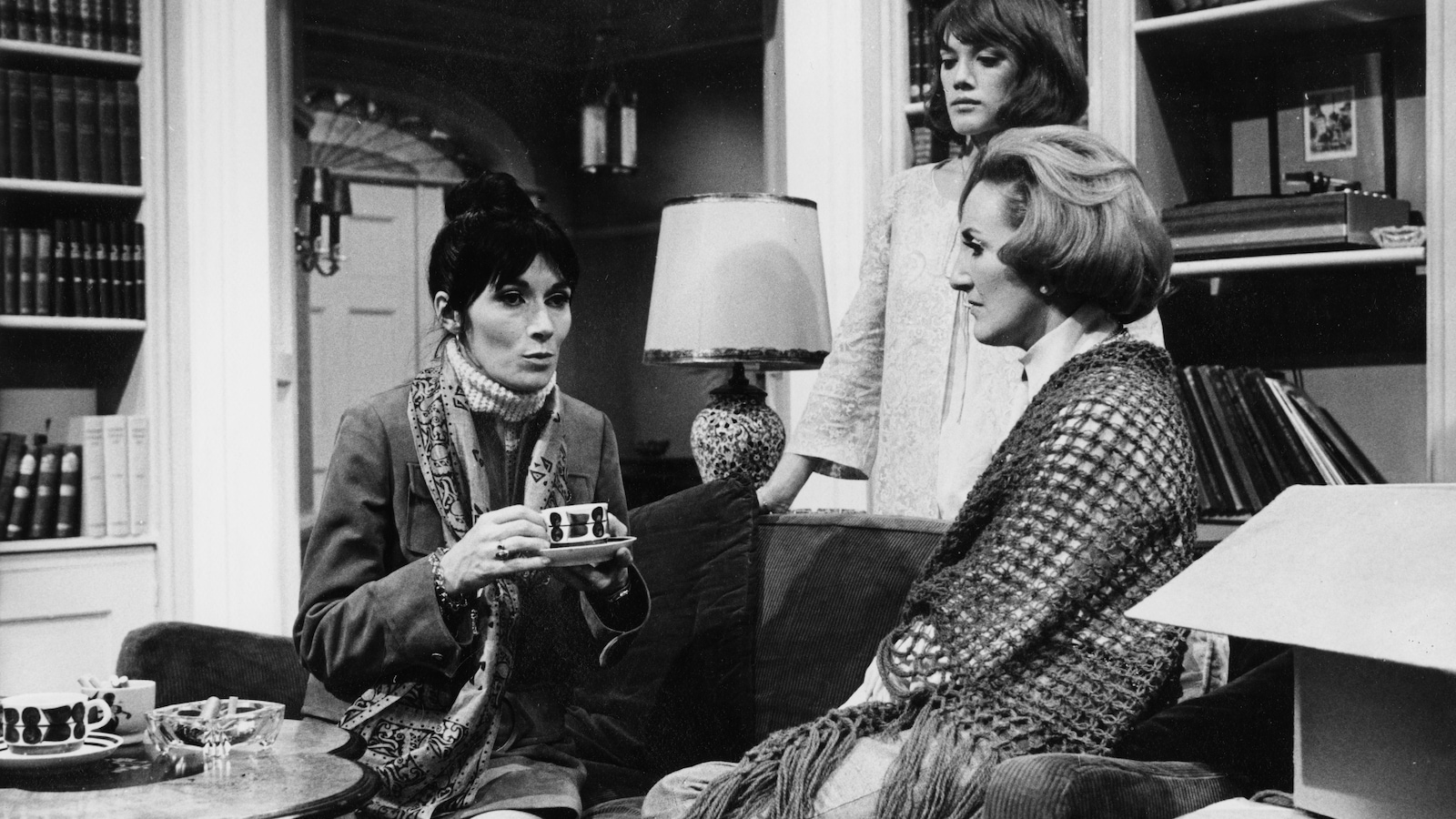 Trois femmes discutent dans un petit salon étroit sur cette photo en noir et blanc de la pièce <i>Une maison… un jour</i>, en 1970. Trois femmes discutent dans un petit salon étroit sur cette photo en noir et blanc de la pièce <i>Une maison… un jour</i>, en 1970.
