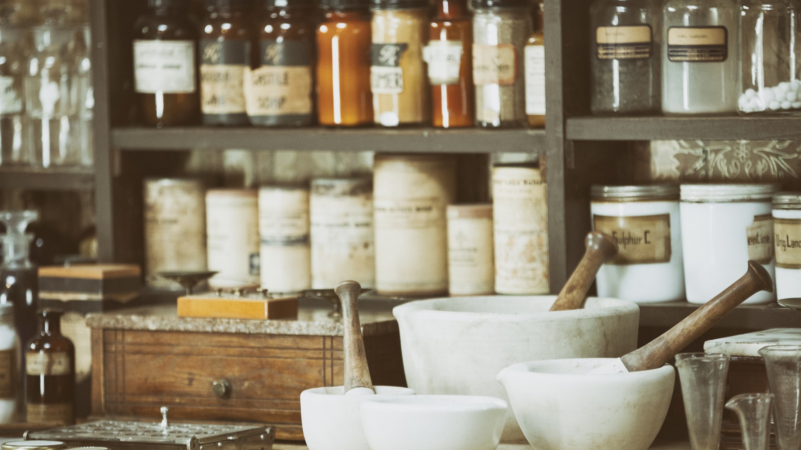 Une pharmacie contient des bouteilles de médicaments sur des tablettes et des mortiers sur une table. Une pharmacie contient des bouteilles de médicaments sur des tablettes et des mortiers sur une table.