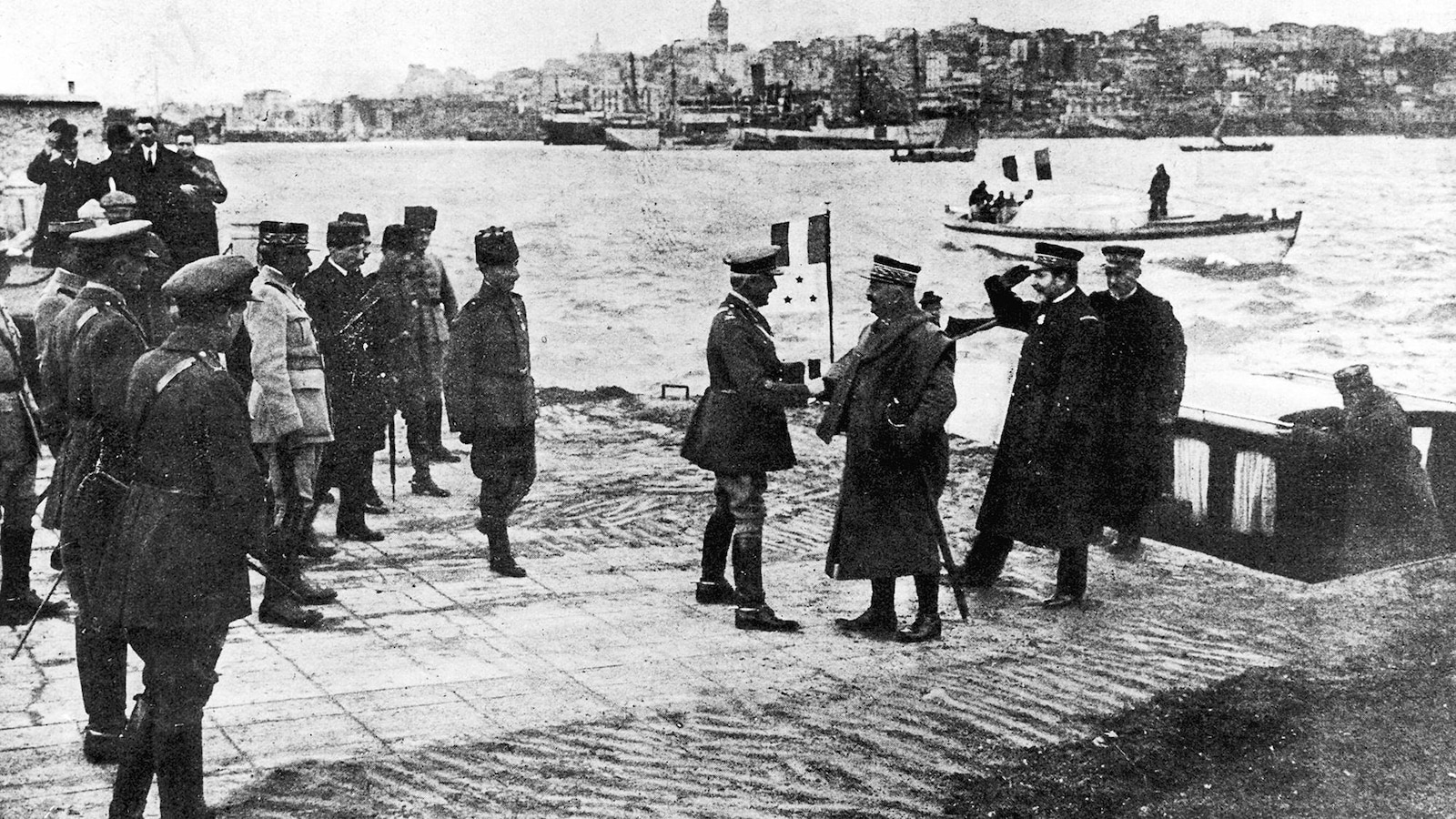 Photo en noir et blanc d'officiers militaires, dont deux se serrent la main, près d'un cours d'eau. Photo en noir et blanc d'officiers militaires, dont deux se serrent la main, près d'un cours d'eau.