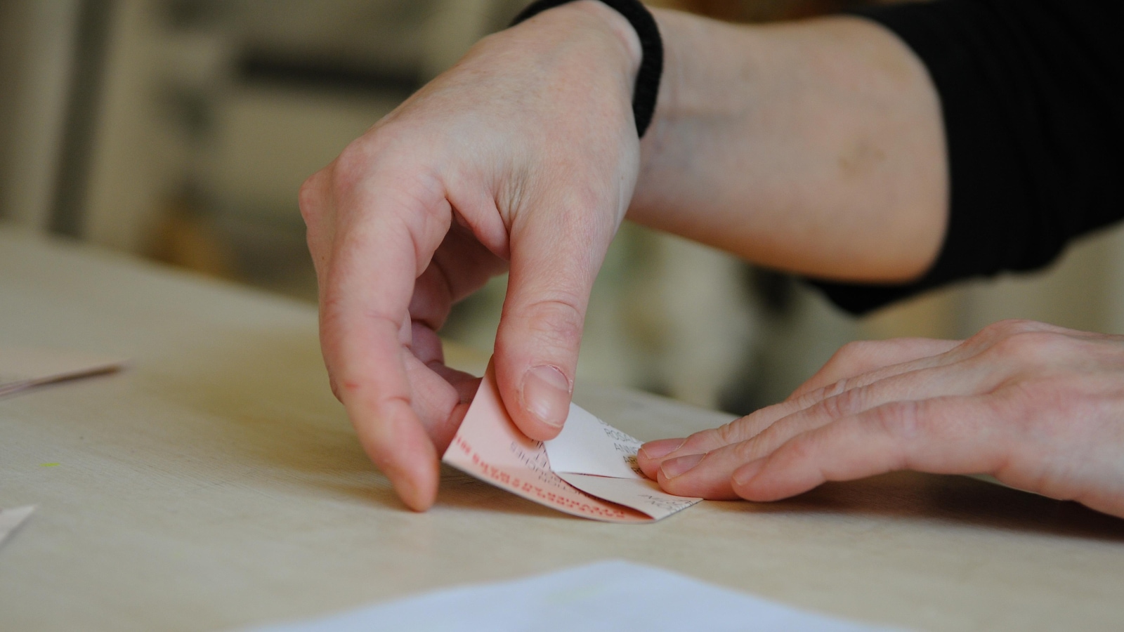 Plan rapproché montrant des mains en train de plier du papier en triangle. Plan rapproché montrant des mains en train de plier du papier en triangle.