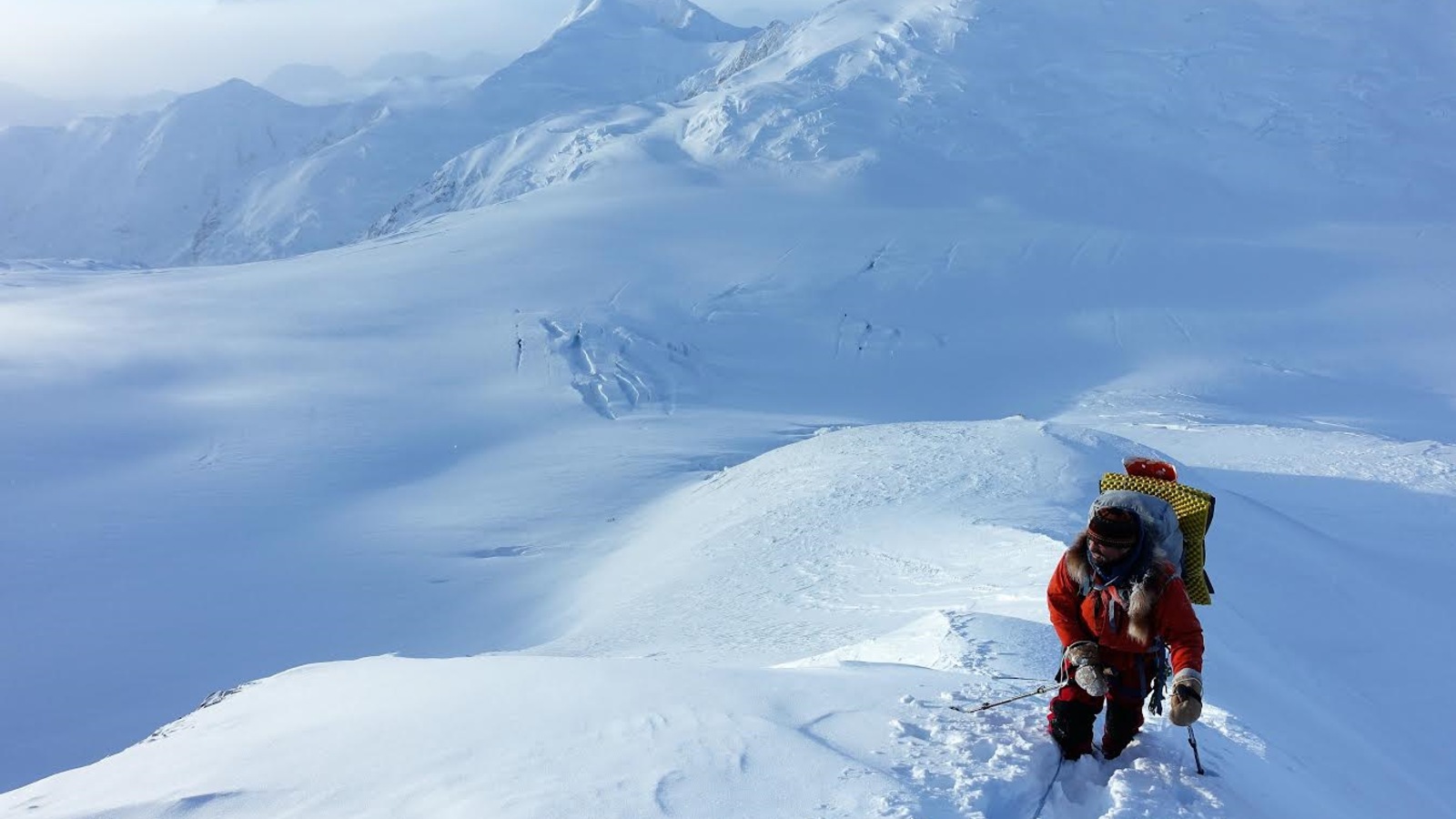 Un homme grimpe une montagne dans un paysage de montagnes complètement couvertes par une épaisse neige. Un homme grimpe une montagne dans un paysage de montagnes complètement couvertes par une épaisse neige.