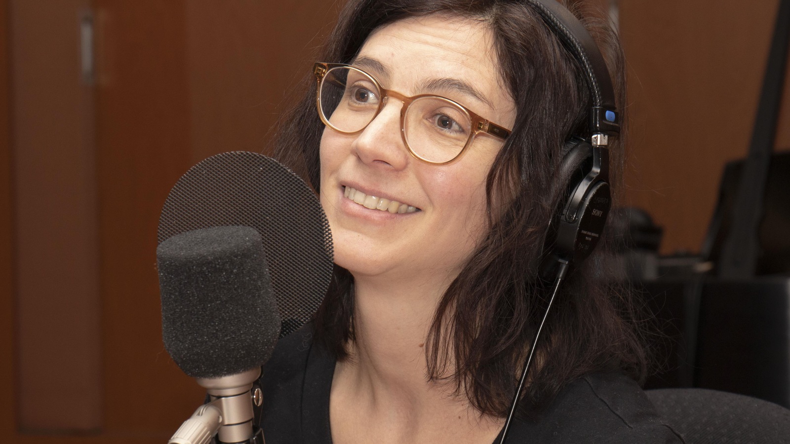 La femme sourit alors qu'elle parle devant un micro. La femme sourit alors qu'elle parle devant un micro.